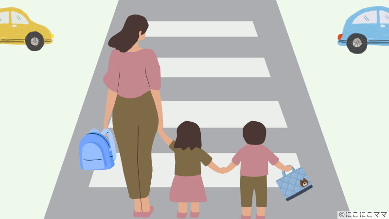 女性と子ども2人が横断歩道で手を繋いで待っているイラスト。