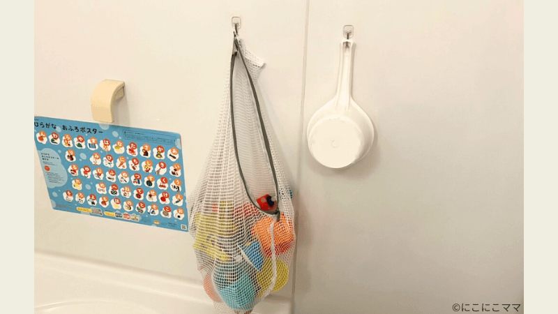 お風呂のおもちゃを洗濯ネットに入れて、吸盤フックで吊るしている収納の実例写真。